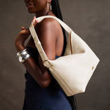Pebbled Bone Large | Model Wearing medium sized slouchy leather shoulder bag with zipper opening and three metal tree emblems