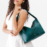 Sea Glass Large | Model wearing medium sized slouchy leather shoulder bag with zipper opening and three metal tree emblems
