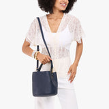 Night Owl Small | Model carrying symmetrical bucket bag with handle, latch closure, and removable crossbody strap