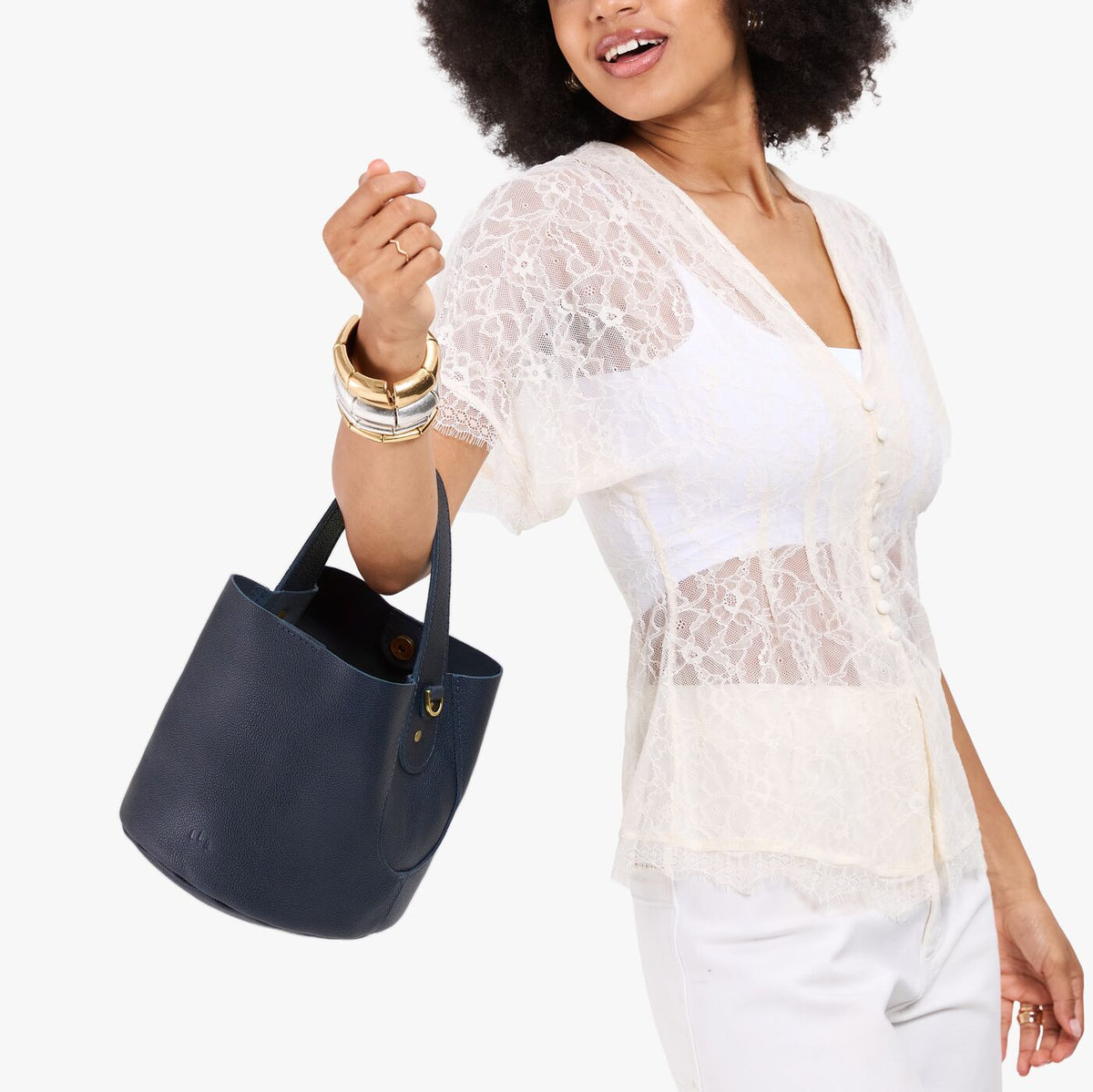 Night Owl*Small | Model carrying symmetrical bucket bag with handle, latch closure, and removable crossbody strap