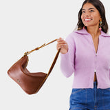 Nutmeg Small | Model holding petite slouchy leather shoulder bag with zipper opening and three metal tree emblems
