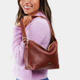 Nutmeg Small | Model holding petite slouchy leather shoulder bag with zipper opening and three metal tree emblems