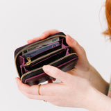 Plum | Model holding small leather wallet with zipper open