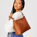 Honey Classic | Model carrying leather triangular shoulder bag with zipper top closure and wide shoulder strap
