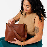 Nutmeg Small | Model holding triangular shoulder bag with antiqued brass finished hardware
