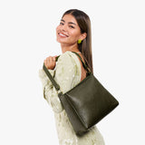 Pebbled Olive Small | Model holding a triangular shoulder bag with antiqued brass finished 