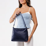 Cobalt Small | Model holding triangular shoulder bag with antiqued brass finished hardware