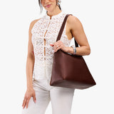 Cognac Large | Model carrying large triangular shoulder bag with antiqued brass finished hardware