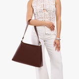 Cognac Large | Model carrying large triangular shoulder bag with antiqued brass finished hardware