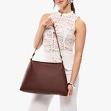 Cognac Large | Model holding large triangular shoulder bag with antiqued brass finished hardware