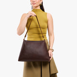 Coldbrew Large | Model holding large triangular shoulder bag with antiqued brass finished hardware