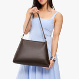 Grizzly Large | Model holding large triangular shoulder bag with antiqued brass finished hardware