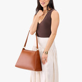Honey Large | Model carrying large triangular shoulder bag with antiqued brass finished hardware