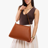 Honey Large | Model holding large triangular shoulder bag with antiqued brass finished hardware