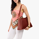 Nutmeg Large | Model carrying large triangular shoulder bag with antiqued brass finished hardware