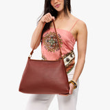 Nutmeg Large | Model holding large triangular shoulder bag with antiqued brass finished hardware