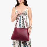 Orchid Large | Model holding large triangular shoulder bag with antiqued brass finished hardware
