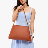 Sienna Large | Model holding large triangular shoulder bag with antiqued brass finished hardware
