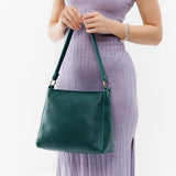 Sea Glass Small | Model holding triangular shoulder bag with antiqued brass finished hardware