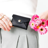 Black | Model holding flowers and small leather wallet with scalloped edge