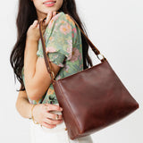 Cognac Classic | Model carrying leather triangular shoulder bag with zipper top closure and wide shoulder strap