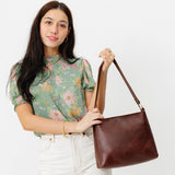 Cognac Small | Model holding triangular shoulder bag with antiqued brass finished hardware